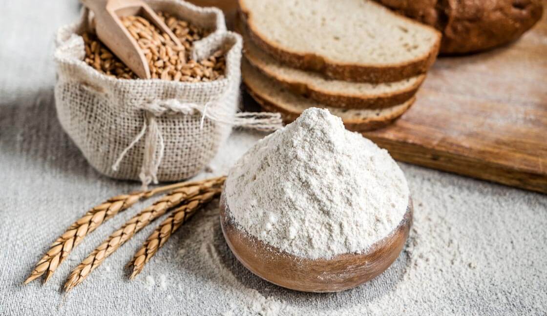 Spelt grain, flour and bread on a table